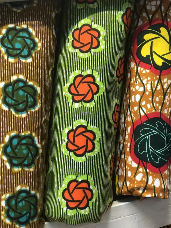 Rolls of wax cloth printed with large green and orange rosettes